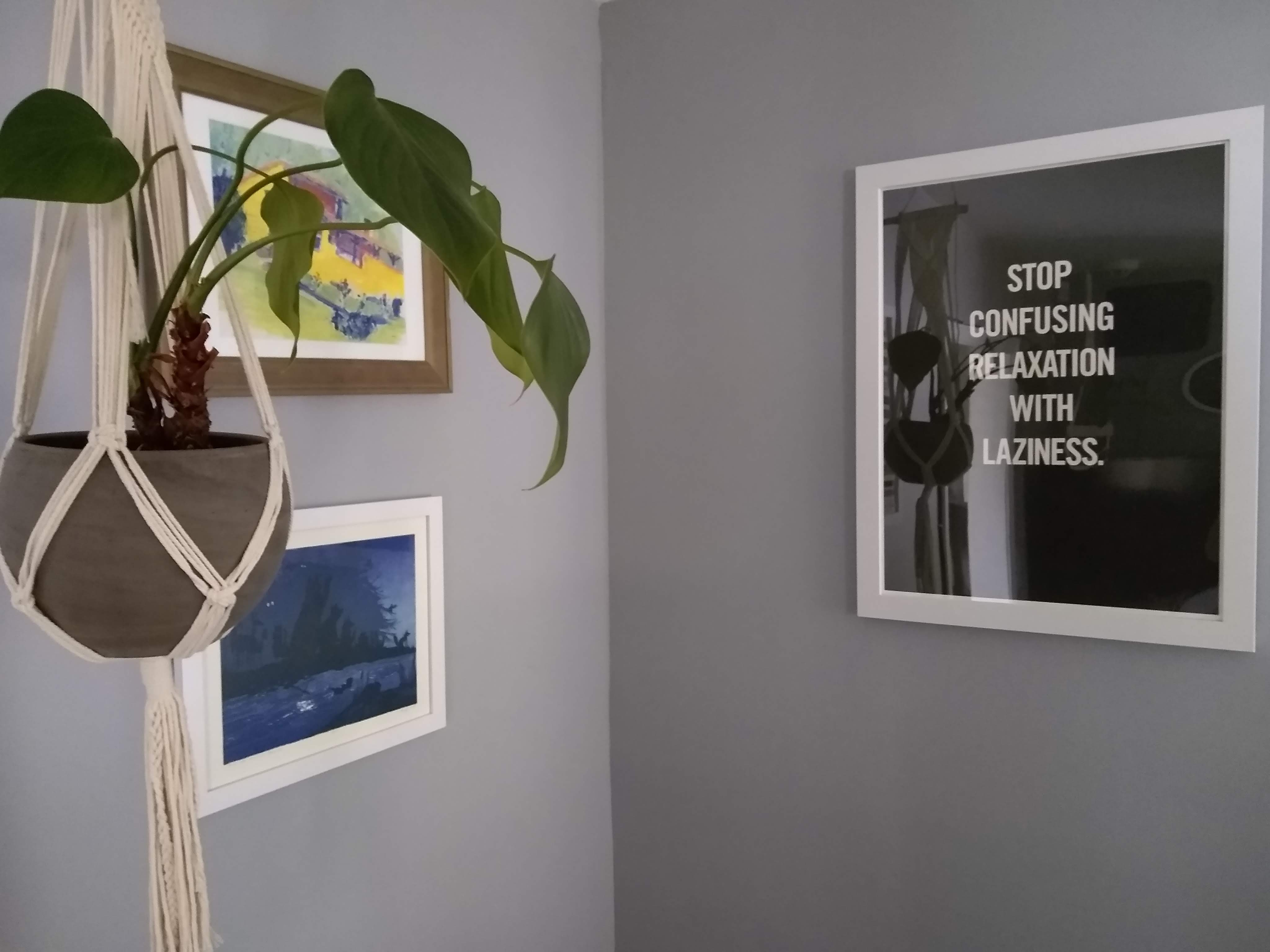 A picture of one corner of the author's living room. On the right side, there's a white-framed poster with a solid black background and text in white capital letters that says 'STOP CONFUSING RELAXATION WITH LAZINESS'.